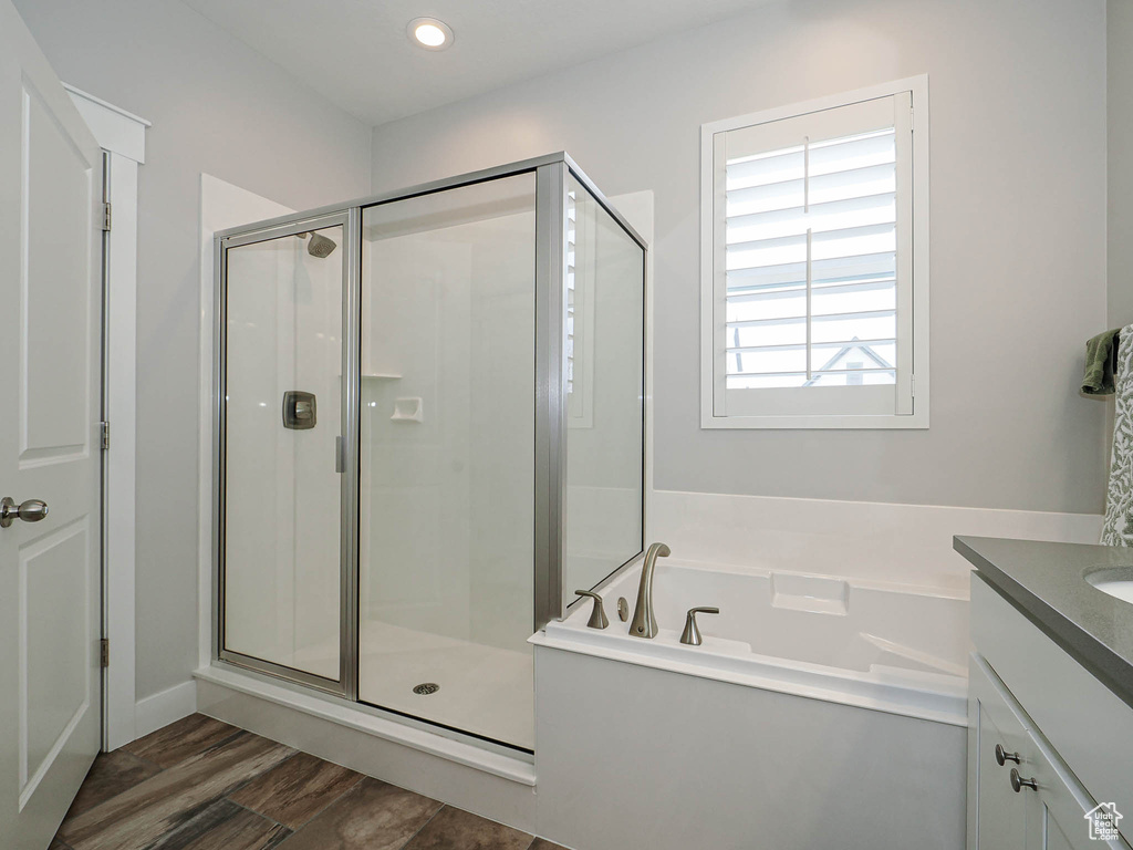 Full bath featuring a stall shower, wood finished floors, vanity, and a garden tub