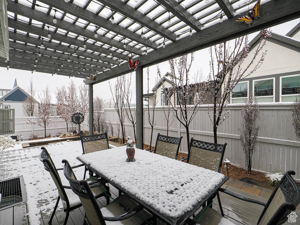 Snow covered patio featuring a fenced backyard, outdoor dining space, and a pergola