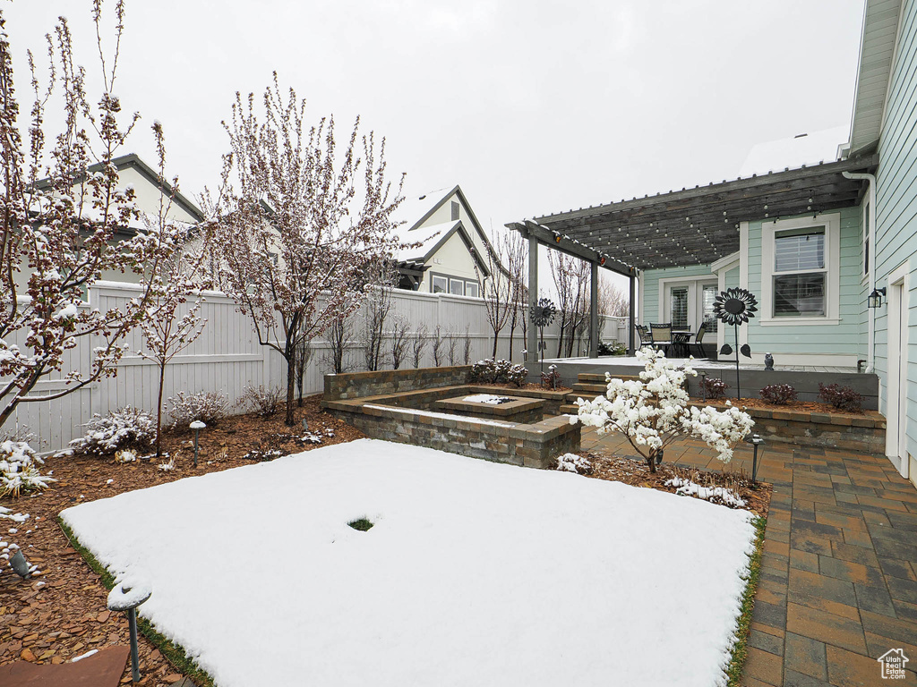 Yard layered in snow with a fenced backyard, a pergola, and a patio