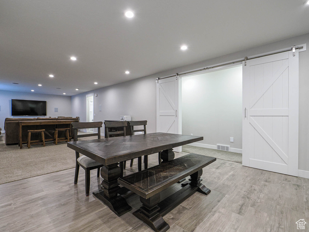 Dining area featuring light wood-style floors, a barn door, visible vents, and recessed lighting