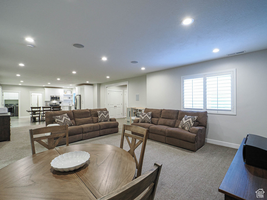 Living area with light carpet, baseboards, visible vents, and recessed lighting