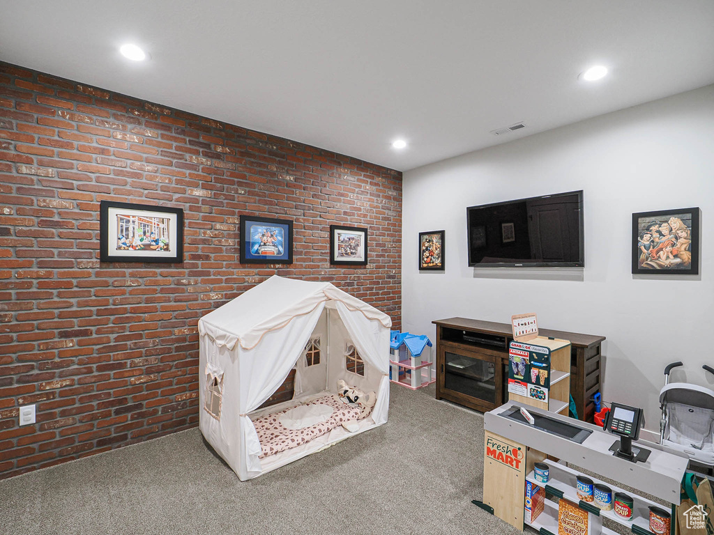 Recreation room featuring carpet flooring, recessed lighting, brick wall, and visible vents