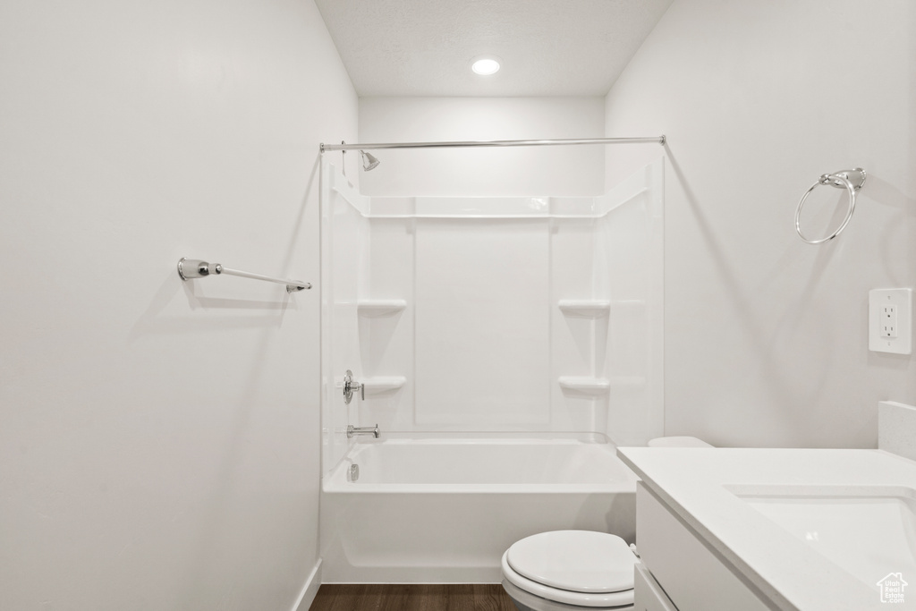 Bathroom featuring vanity, wood finished floors, toilet, baseboards, and shower / bath combination