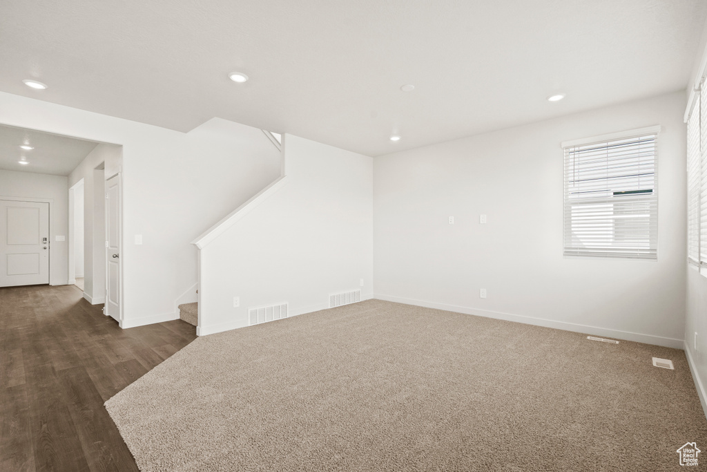 Unfurnished living room with stairs, baseboards, and visible vents