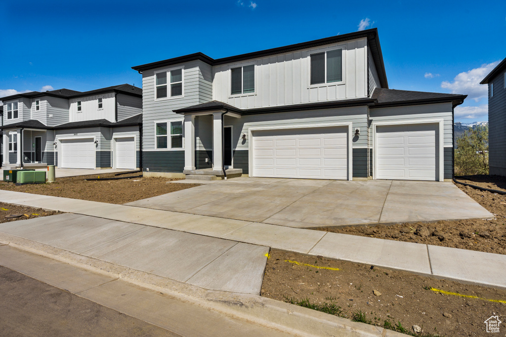View of front of house with a garage, board and batten siding, central AC, and driveway