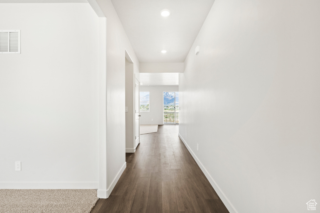 Hall featuring dark wood finished floors, baseboards, recessed lighting, and visible vents