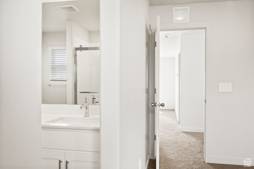 Bathroom featuring visible vents, a shower with shower door, and vanity