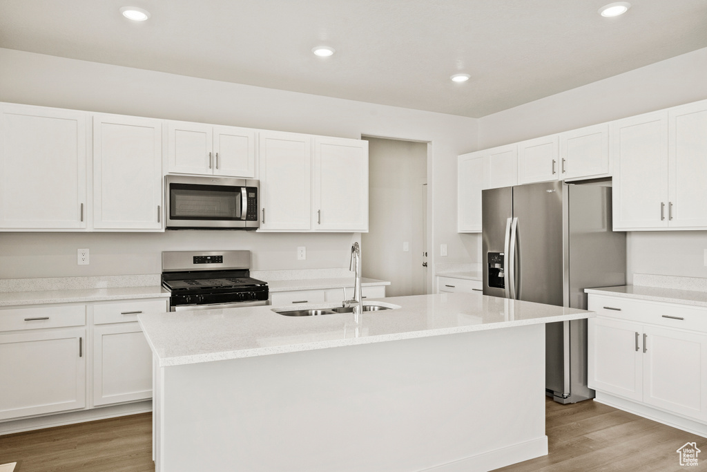 Kitchen featuring a sink, white cabinetry, appliances with stainless steel finishes, and light wood-style flooring