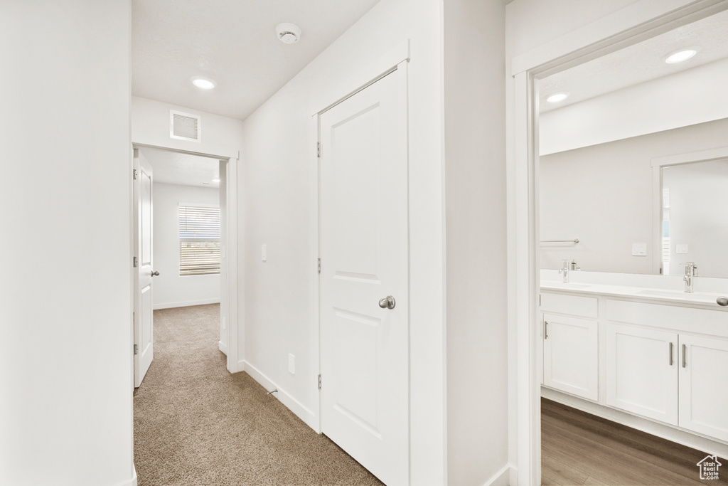 Hallway featuring recessed lighting, baseboards, visible vents, and a sink