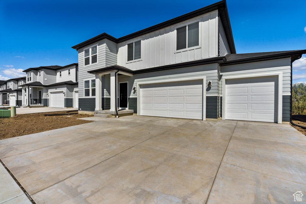 View of front of property featuring board and batten siding, driveway, and a garage
