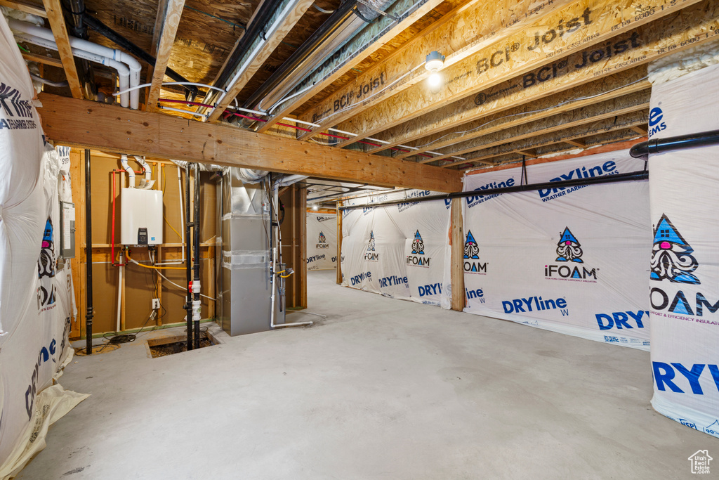 Unfinished basement featuring heating unit and tankless water heater
