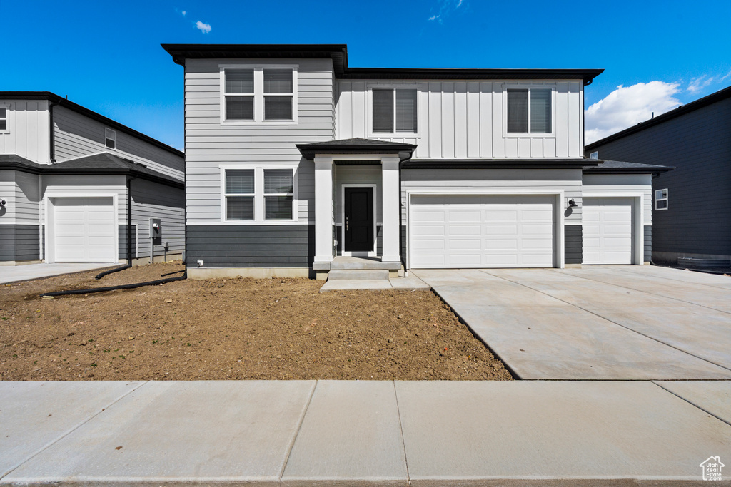 View of front of house with an attached garage, board and batten siding, and driveway
