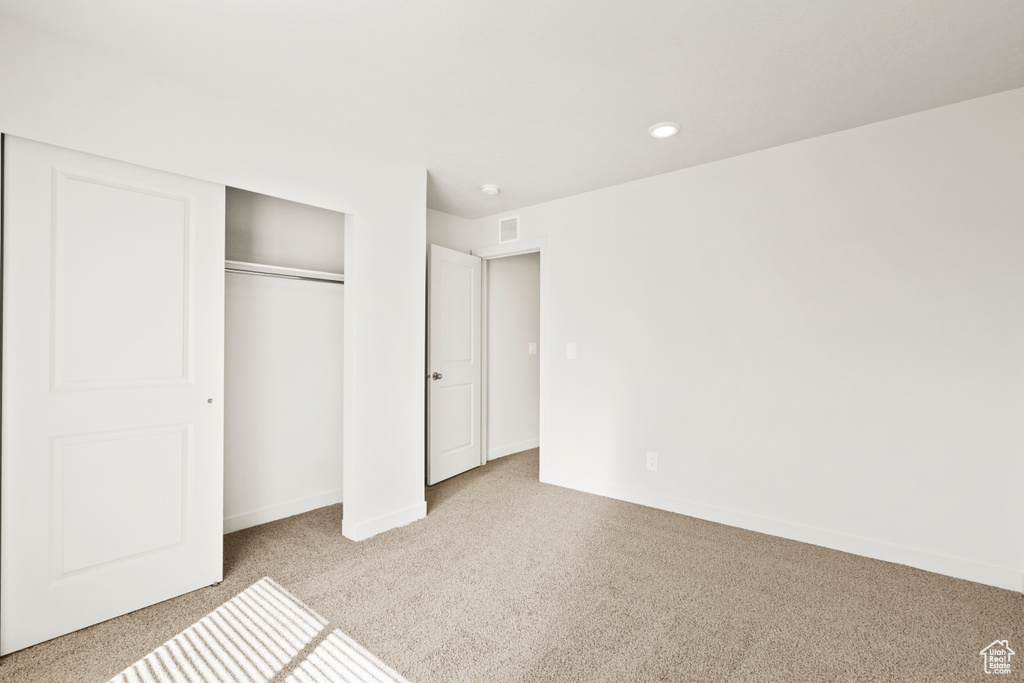 Unfurnished bedroom with carpet flooring, recessed lighting, baseboards, visible vents, and a closet