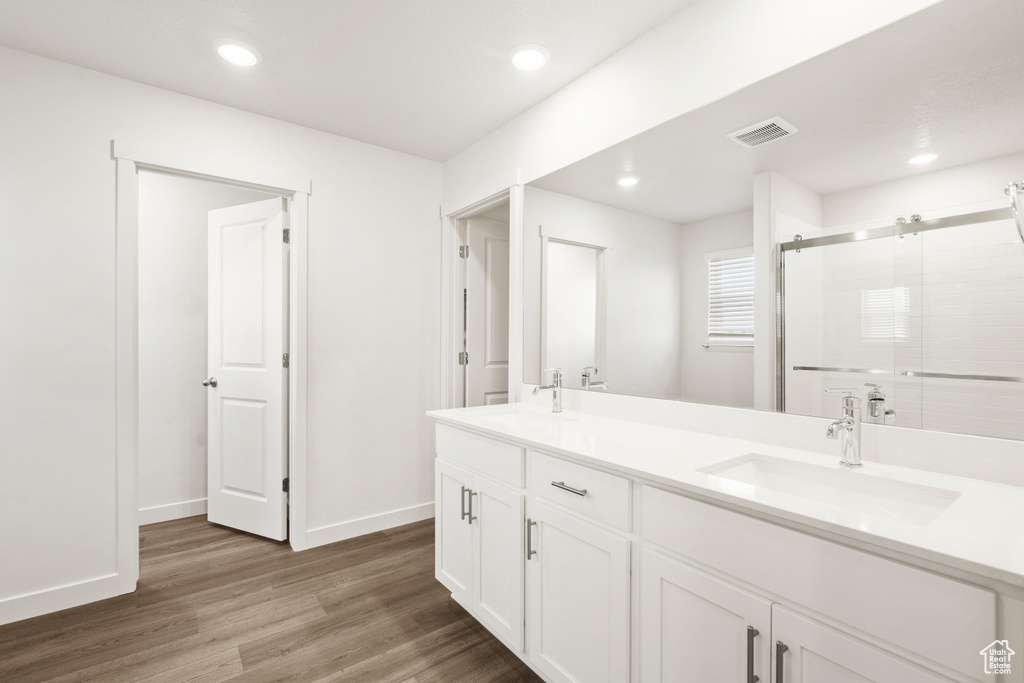Bathroom with wood finished floors, visible vents, a sink, and a stall shower
