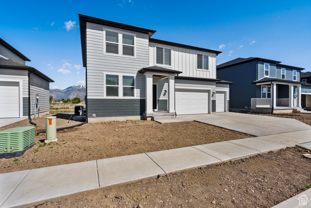 Traditional-style house featuring an attached garage, board and batten siding, a mountain view, and concrete driveway