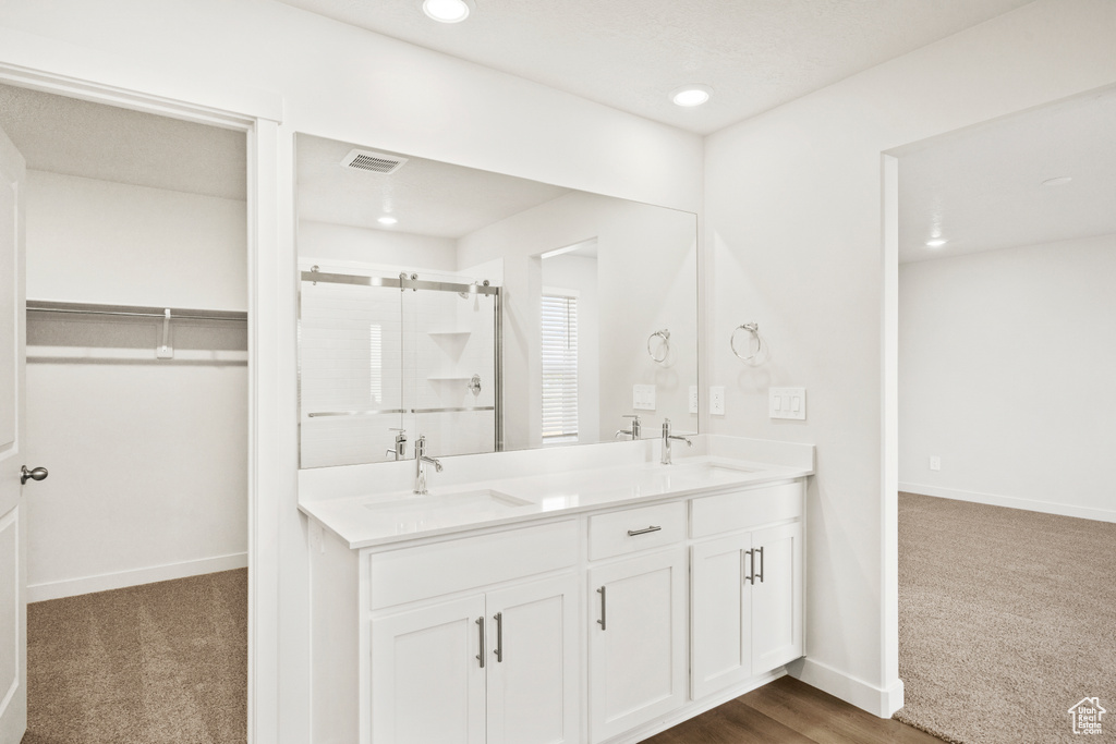 Full bath featuring a sink, double vanity, a spacious closet, visible vents, and a stall shower