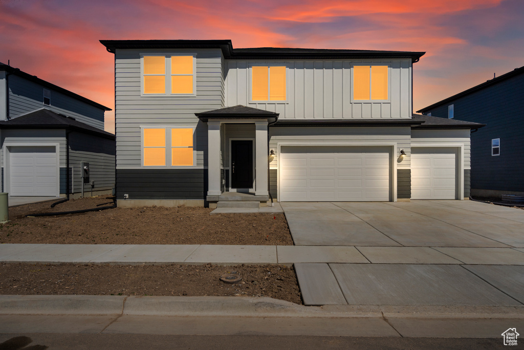 View of front of house with an attached garage, board and batten siding, and concrete driveway