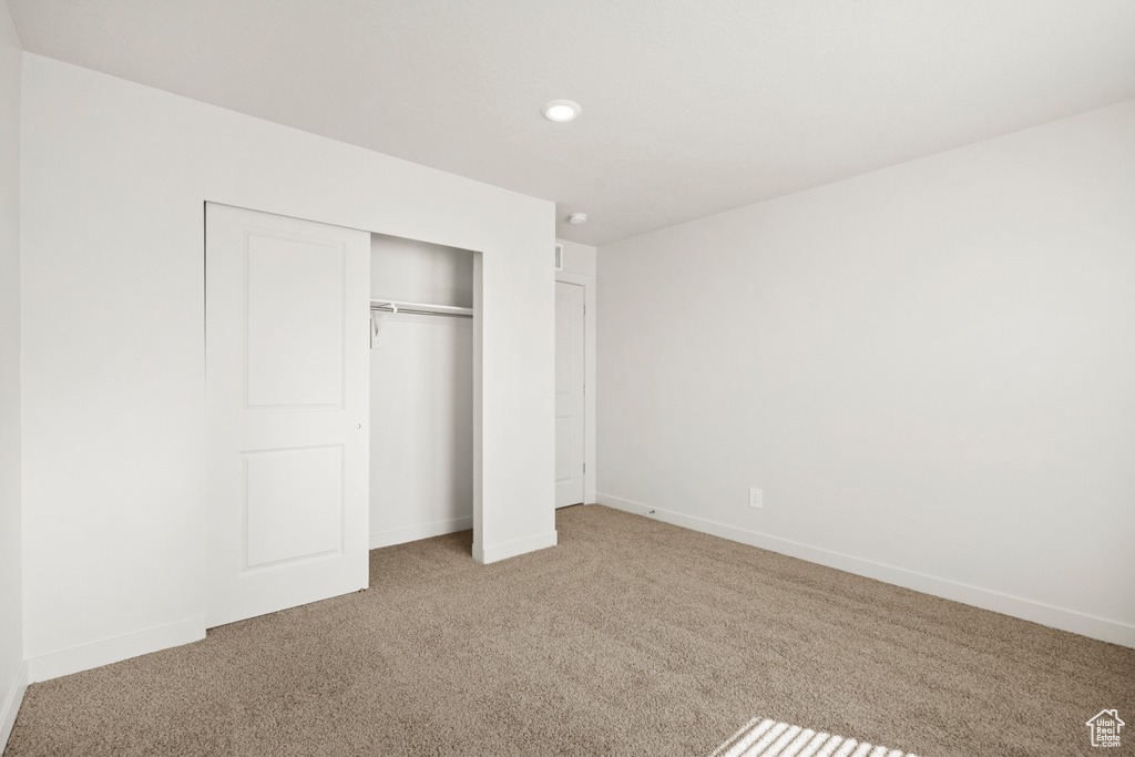 Unfurnished bedroom featuring baseboards, light carpet, a closet, and recessed lighting