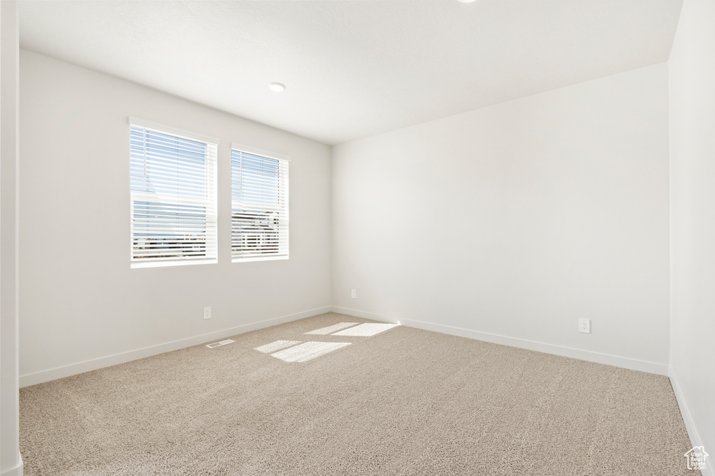 Unfurnished room featuring baseboards, visible vents, and light carpet