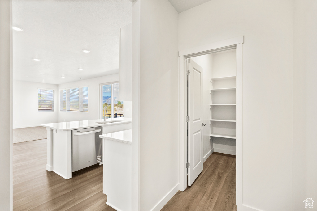 Hallway featuring baseboards, a sink, wood finished floors, and recessed lighting
