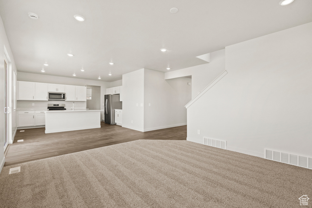 Unfurnished living room featuring baseboards, recessed lighting, wood finished floors, and visible vents