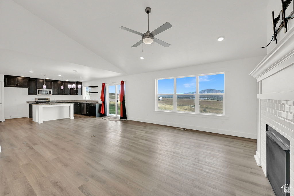 Unfurnished living room with recessed lighting, a fireplace, a ceiling fan, light wood-style floors, and high vaulted ceiling