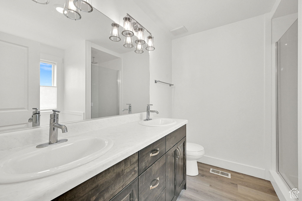 Full bathroom with wood finished floors, a shower with door, and double vanity