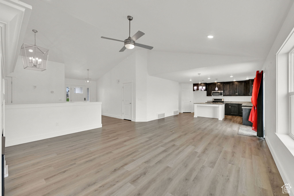 Unfurnished living room with a chandelier, recessed lighting, high vaulted ceiling, light wood finished floors, and a ceiling fan