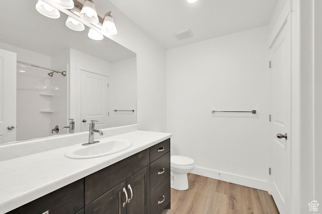 Full bath with vanity, wood finished floors, and a shower