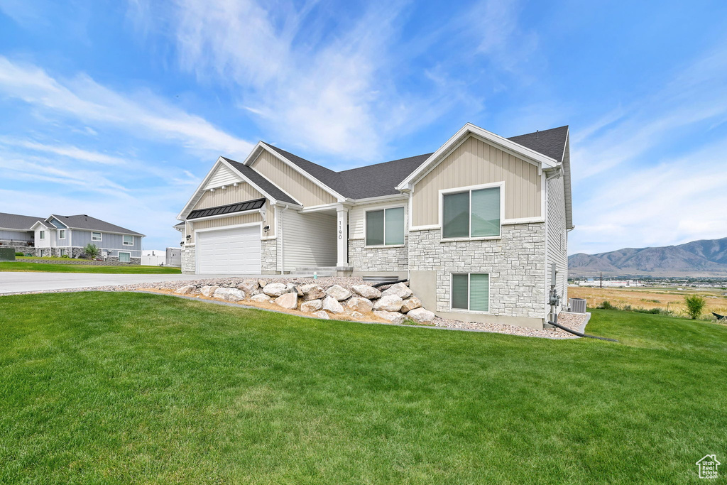 Craftsman-style home with stone siding, board and batten siding, a front yard, and driveway
