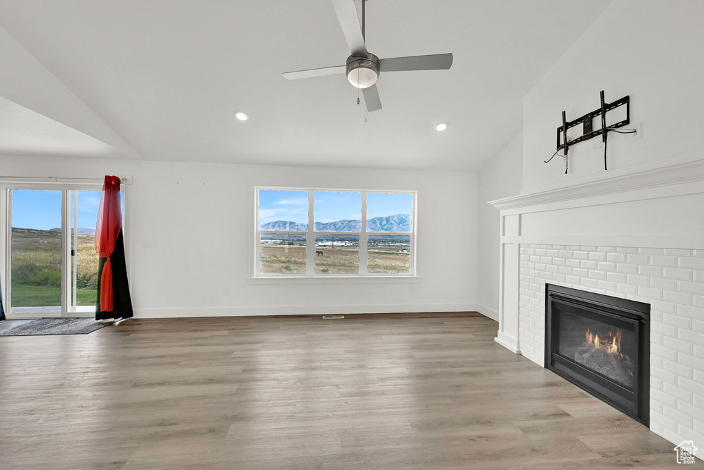 Unfurnished living room featuring plenty of natural light, a fireplace, a ceiling fan, recessed lighting, and wood finished floors