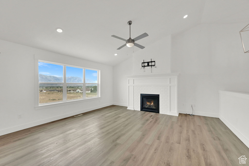 Unfurnished living room featuring ceiling fan, a fireplace, light wood-style floors, recessed lighting, and high vaulted ceiling
