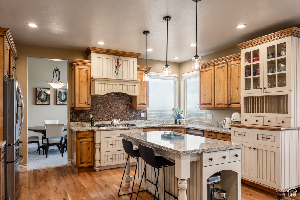 Kitchen featuring a kitchen island, a sink, stainless steel appliances, and light wood-type flooring