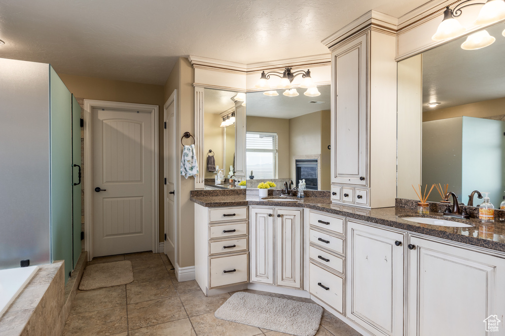Bathroom featuring double vanity, a sink, tile patterned flooring, and an enclosed shower