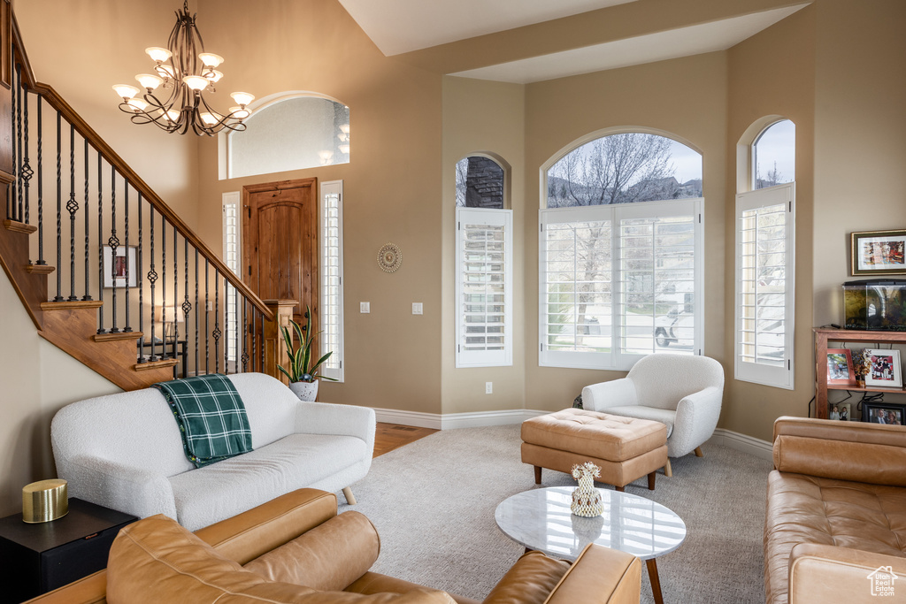 Living room featuring baseboards, a wealth of natural light, an inviting chandelier, and stairway