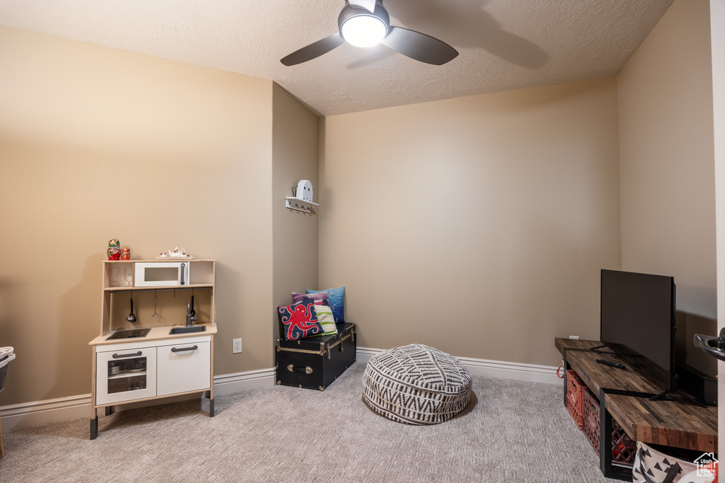 Playroom with baseboards, a textured ceiling, carpet flooring, and a ceiling fan