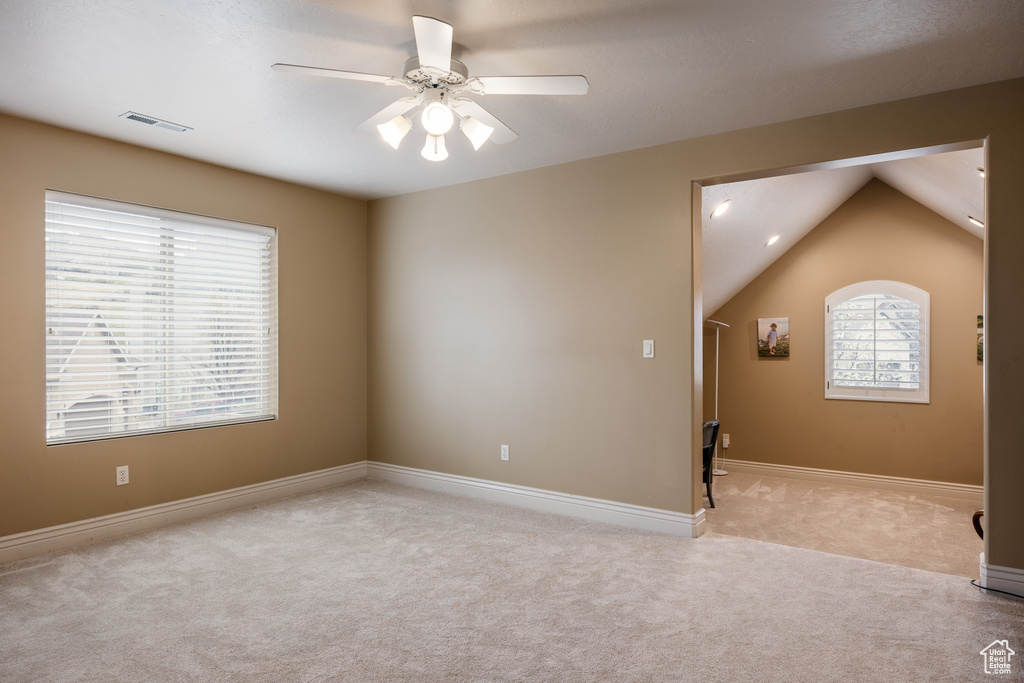 Unfurnished room featuring a ceiling fan, lofted ceiling, baseboards, visible vents, and carpet