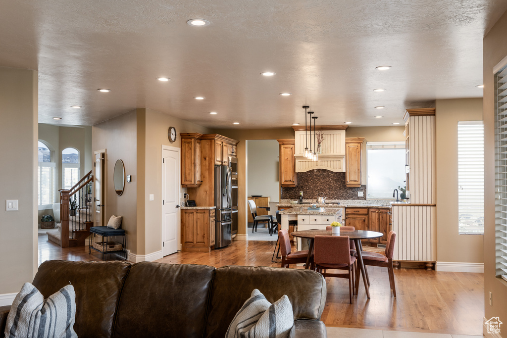 Living room featuring stairs, baseboards, light wood finished floors, and recessed lighting