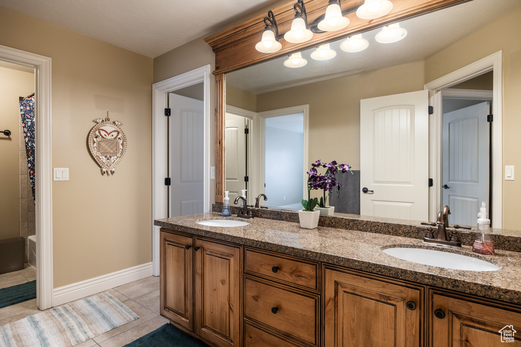 Bathroom with tile patterned floors, a sink, double vanity, and baseboards
