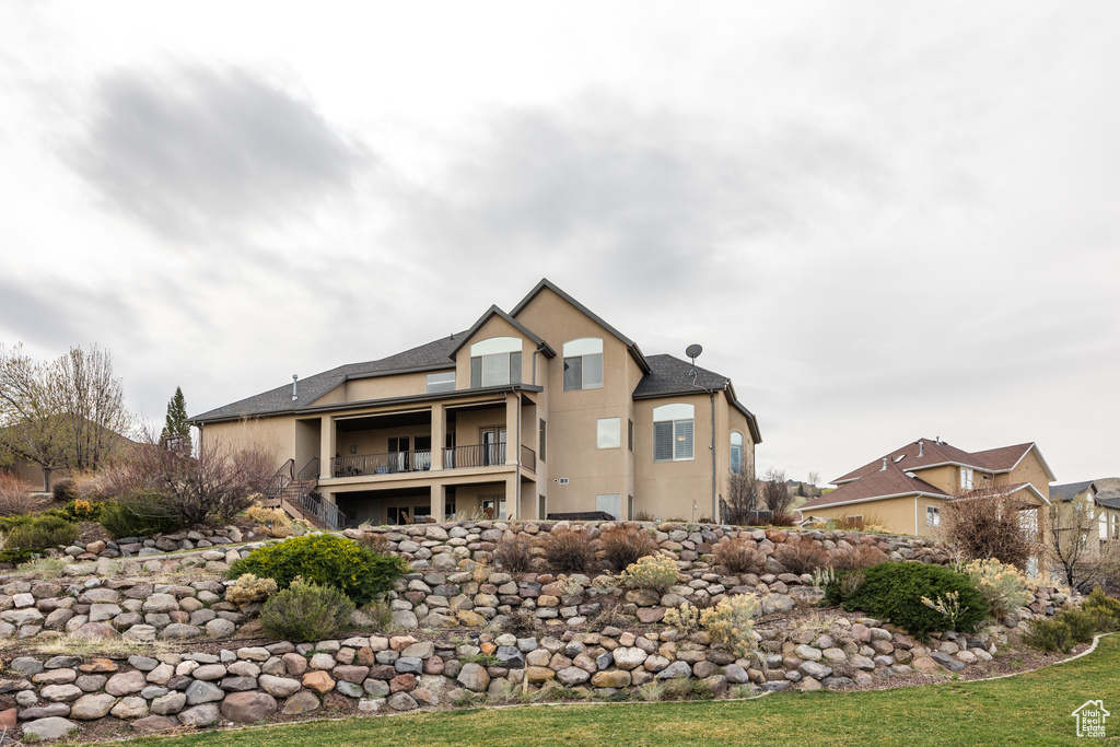 Rear view of house with stucco siding and a balcony