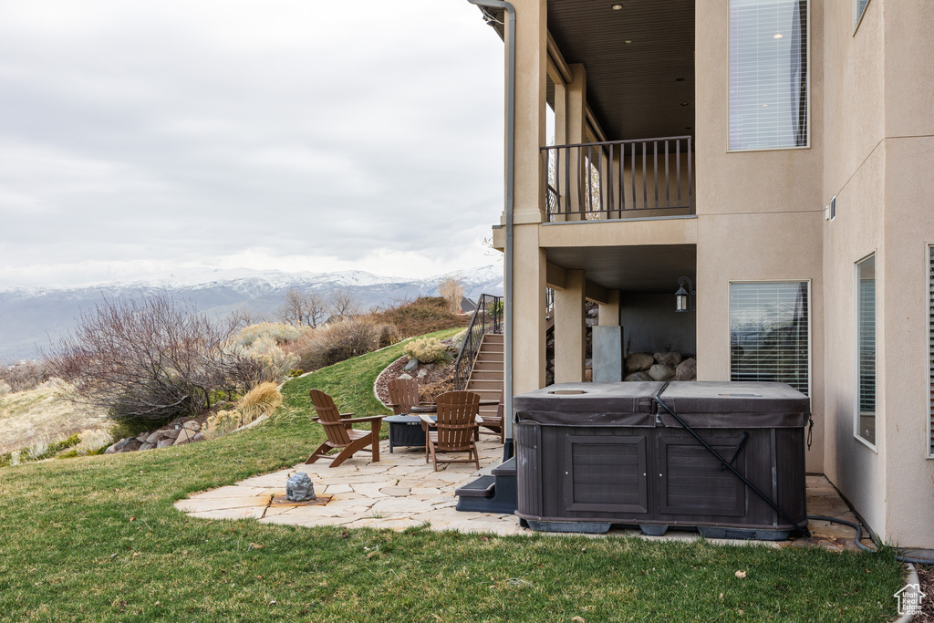 View of yard featuring stairs, a mountain view, a hot tub, and a patio