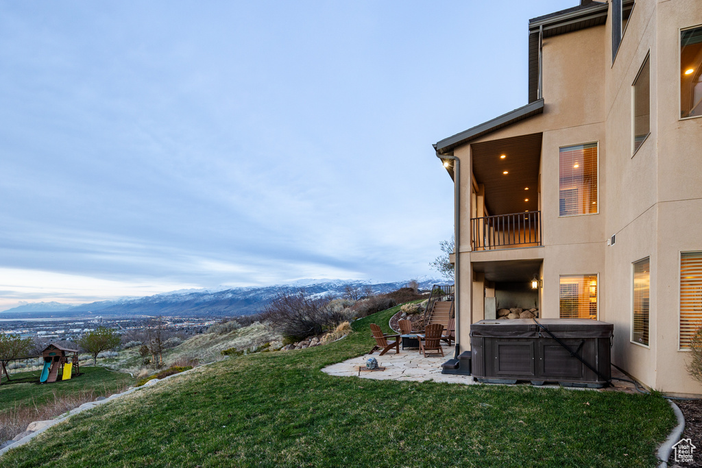View of yard featuring a patio area, a mountain view, a balcony, and a hot tub