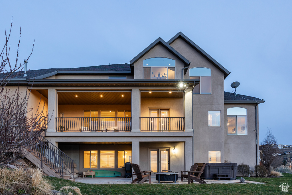Rear view of house featuring a patio, a balcony, stucco siding, stairs, and an outdoor fire pit