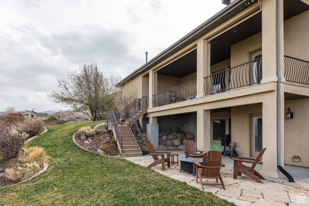 Rear view of house featuring a yard, stucco siding, stairway, and a patio area