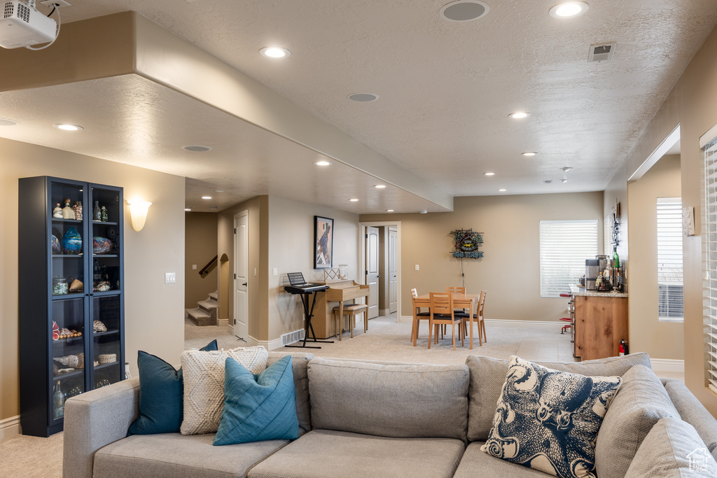 Living area featuring stairs, baseboards, recessed lighting, and a textured ceiling