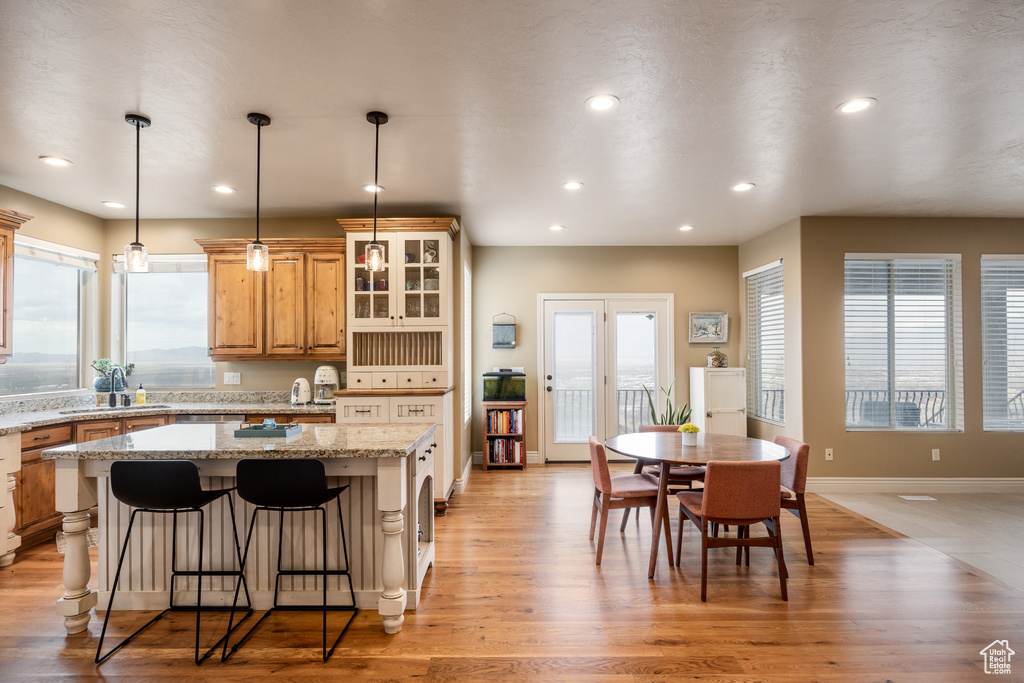 Kitchen with a center island, glass insert cabinets, light wood-style floors, and recessed lighting