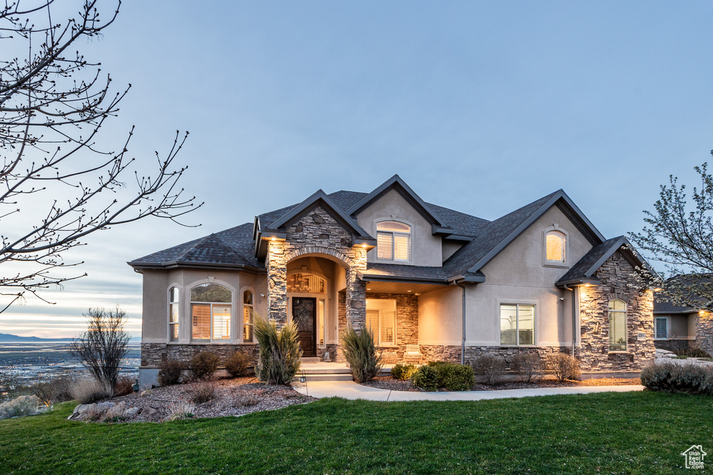 French provincial home with a front yard, stucco siding, and stone siding