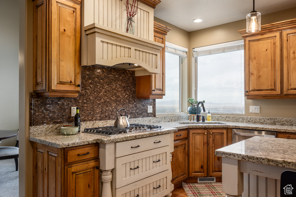 Kitchen with a sink, stainless steel appliances, brown cabinets, and tasteful backsplash