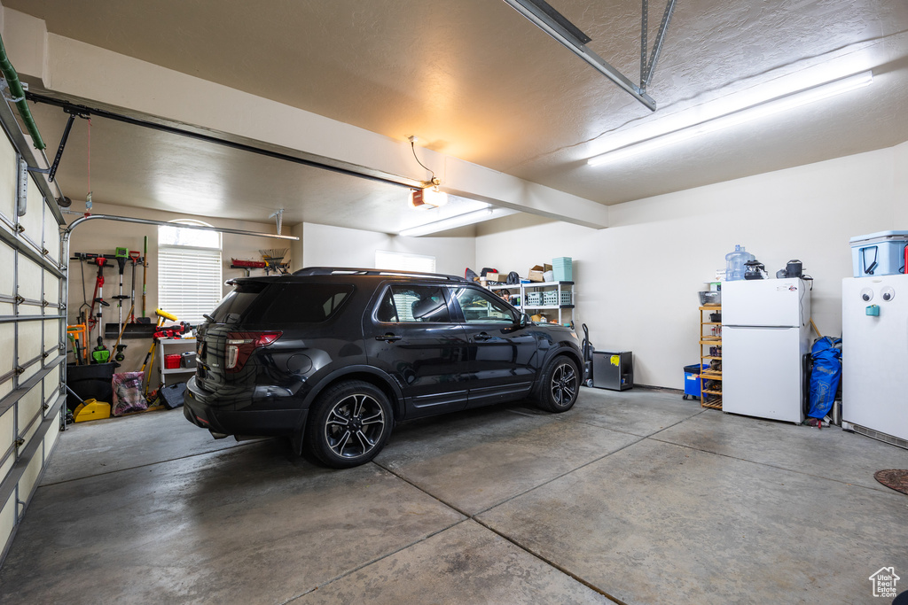 Garage featuring freestanding refrigerator and a garage door opener