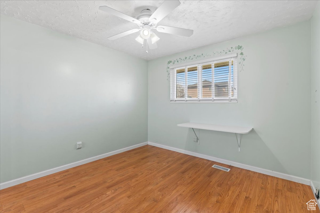 Spare room with baseboards, ceiling fan, visible vents, and wood finished floors